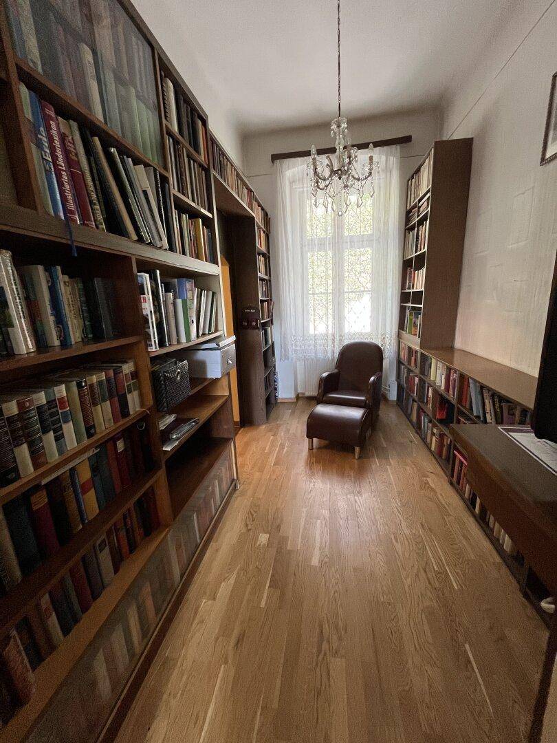 Gemütliche Bibliothek mit raumhohen Bücherregalen und Holzboden.