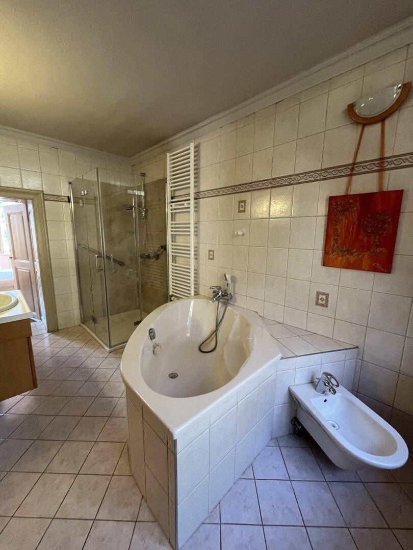 Badezimmer mit Dusche, Eckbadewanne, Bidet und Fliesenboden.