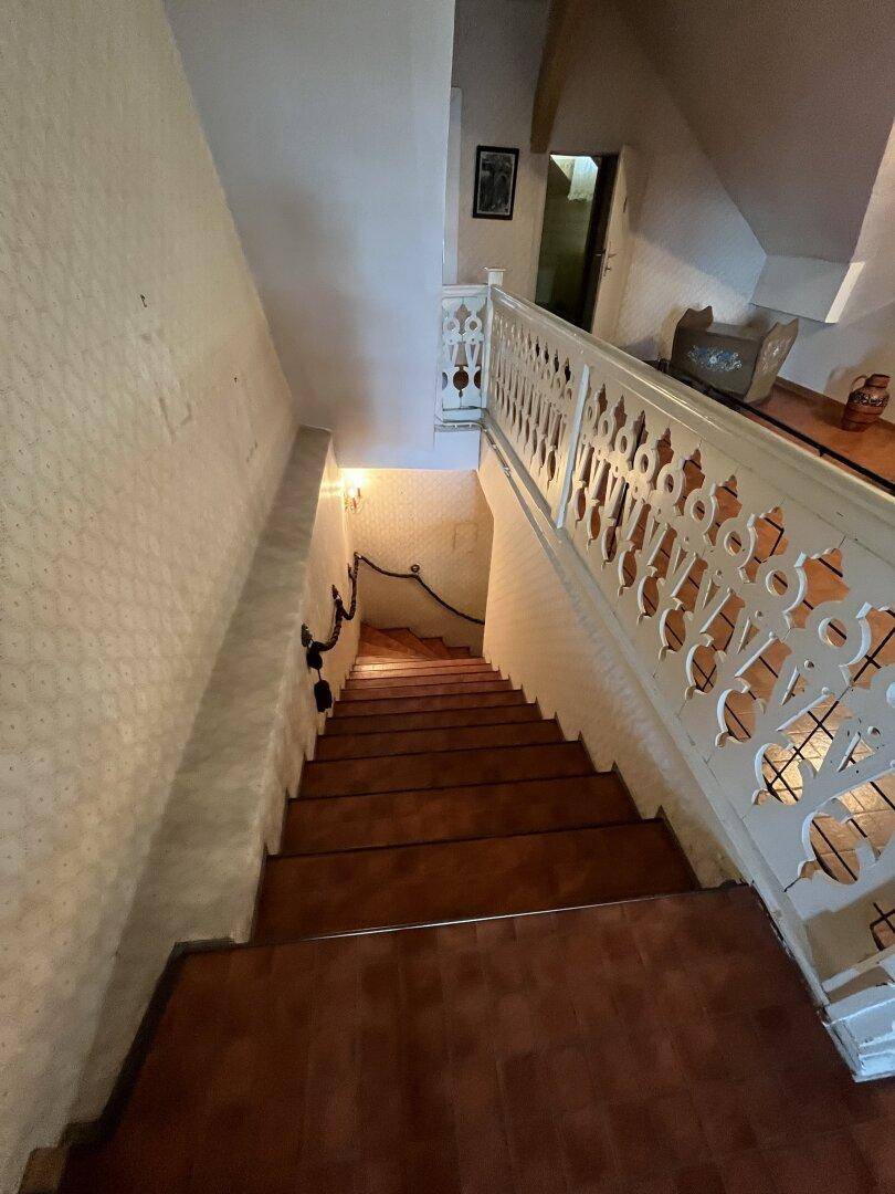 Treppenhaus mit traditionellem Holzgeländer und Fliesenstufen.