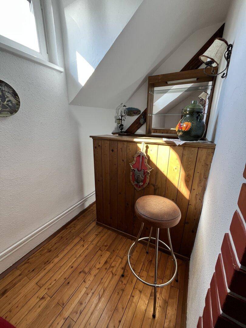 Gemütliche Bar im Dachgeschoss mit Holztäfelung und Dachfenster.