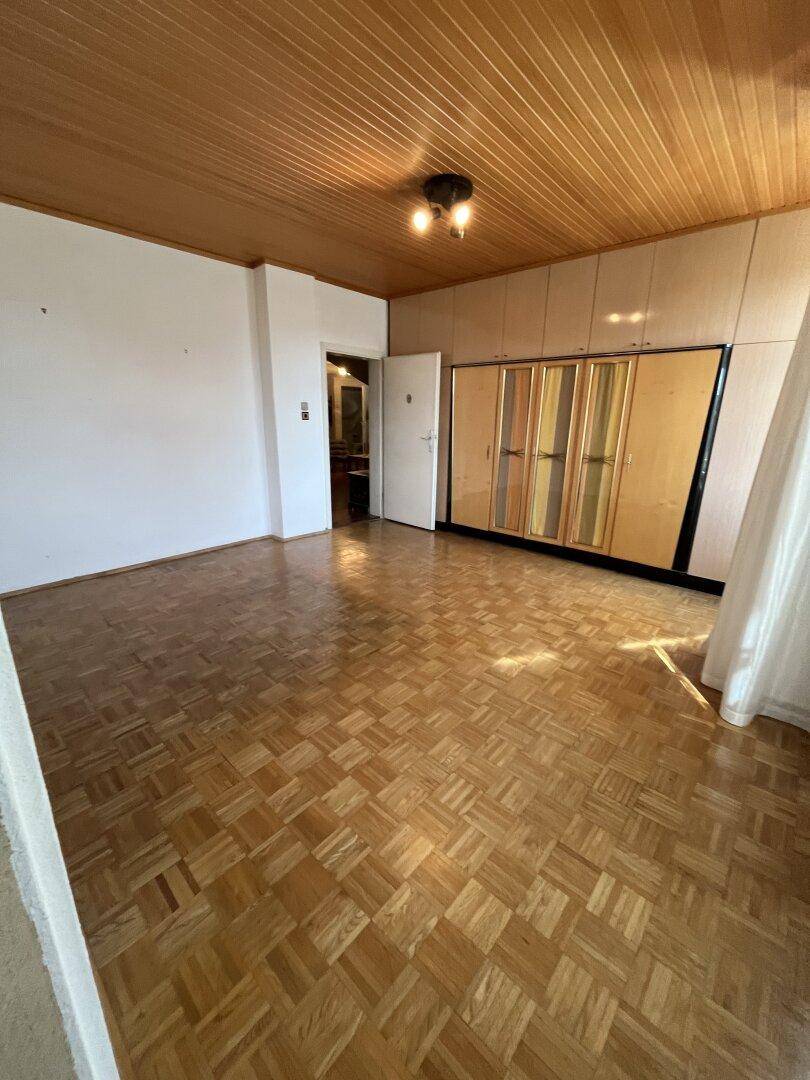 Schlafzimmer mit Parkettboden, Holzdecke und Einbauschränken.