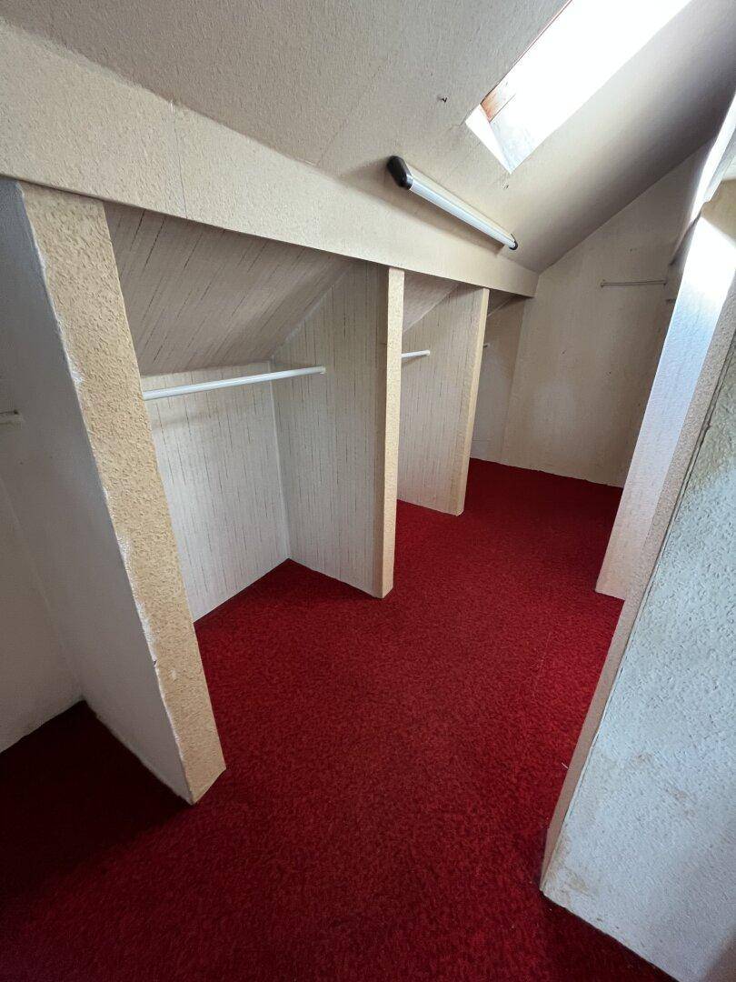 Begehbarer Kleiderschrank im Dachgeschoss mit rotem Teppichboden und Dachfenster.