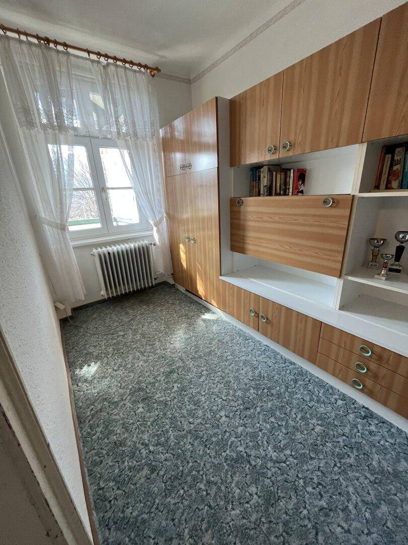 Kleines Zimmer mit Linoleumboden, Einbauschränken und Fenster.