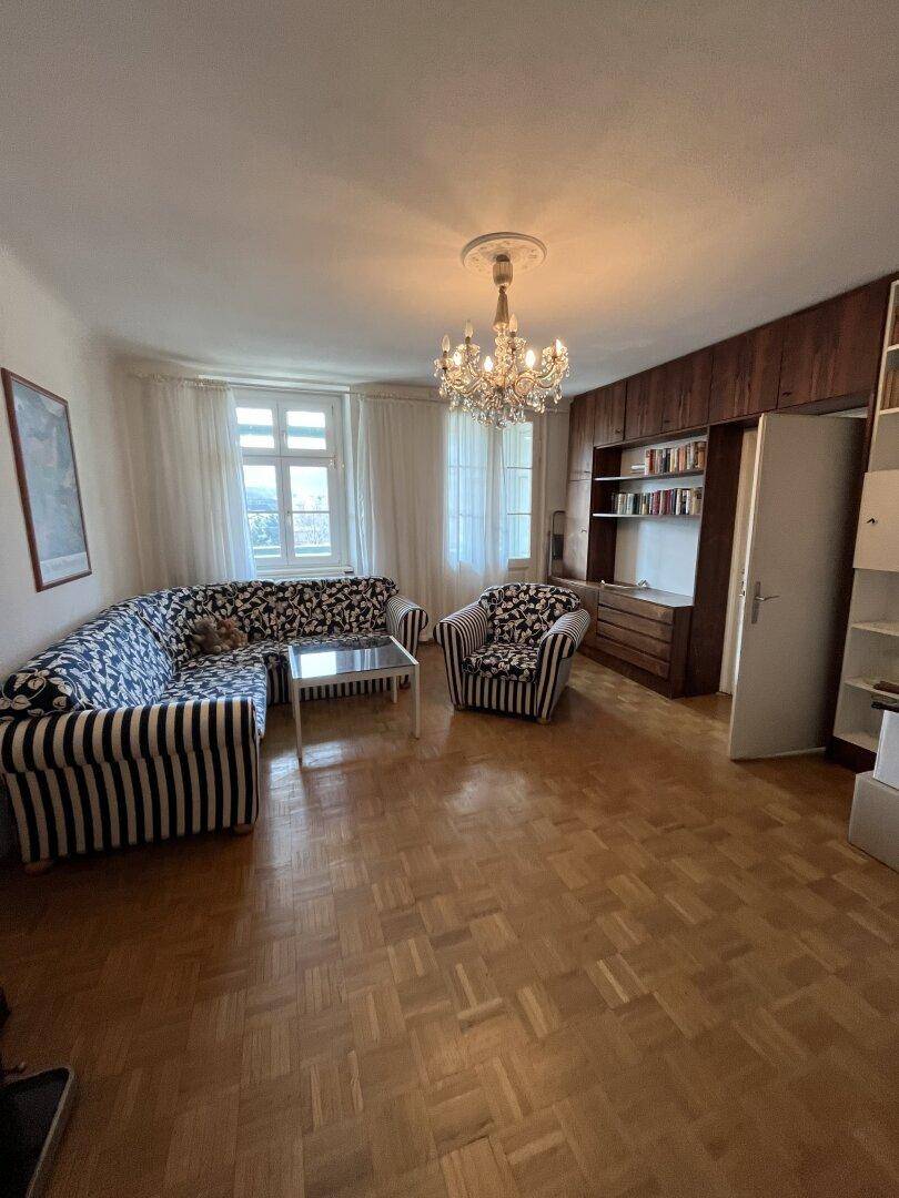 Helles Wohnzimmer mit Parkettboden, gestreiftem Sofa und Kronleuchter.