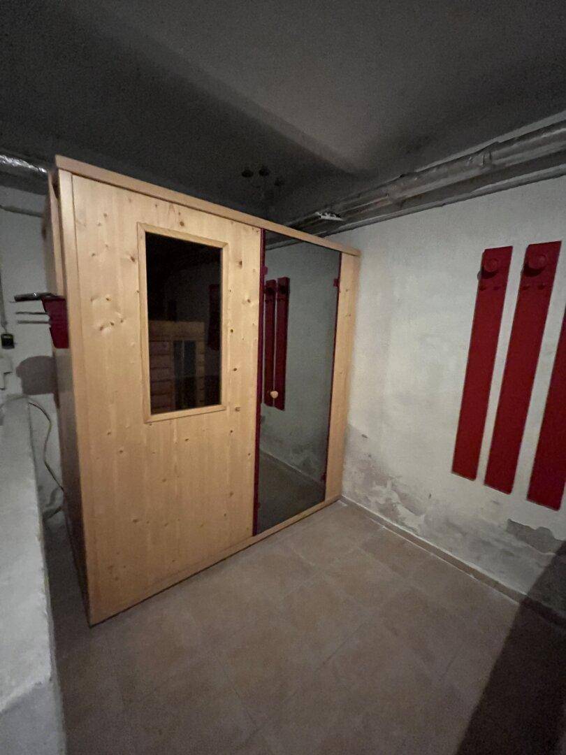 Sauna im Kellerbereich mit Holztür und Spiegel.