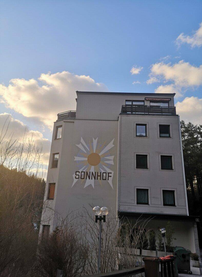 Ansicht der Gebäudefassade mit "Sonnhof"-Schriftzug und Balkonen unter blauem Himmel.
