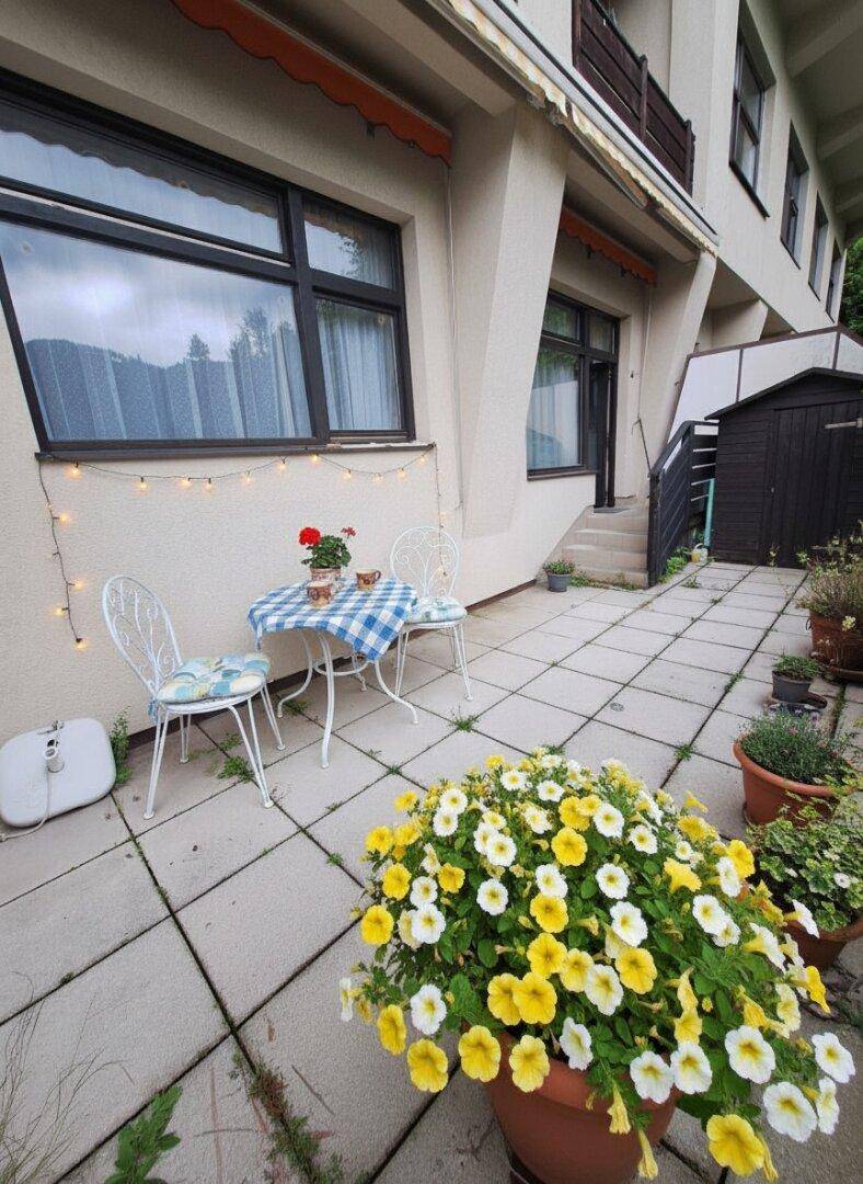 Gemütliche Terrasse im Erdgeschoss mit Sitzgelegenheiten und Blumenkübeln.