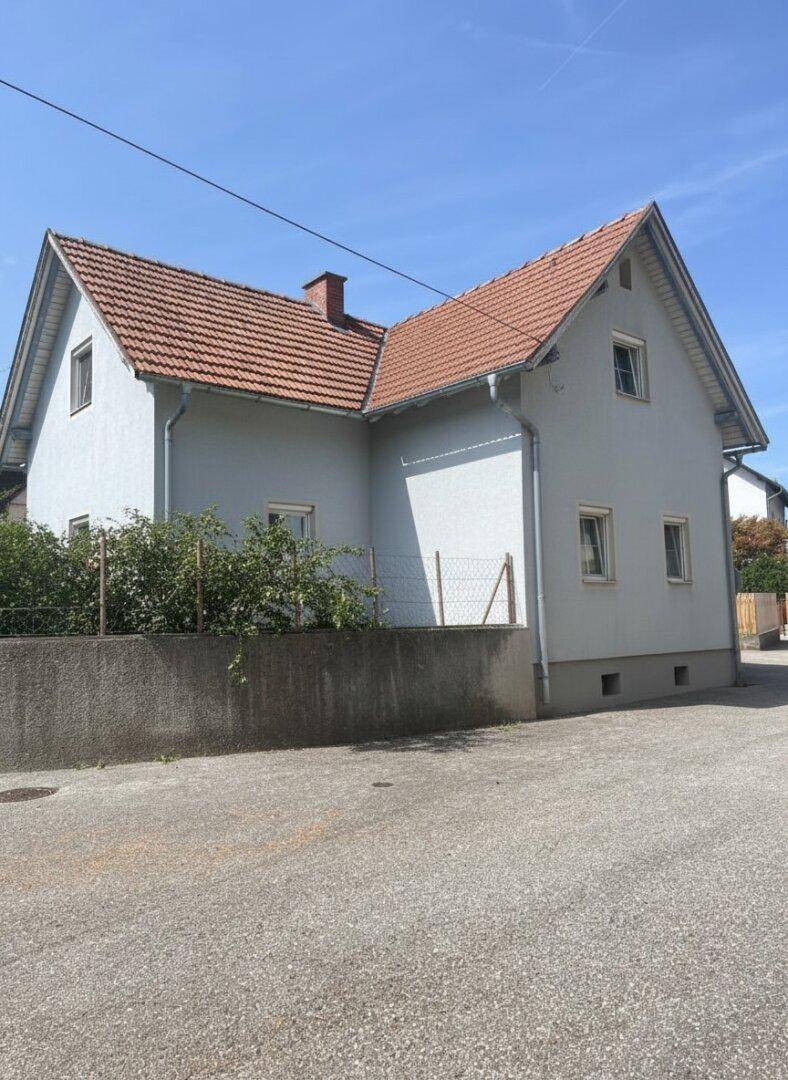 Außenansicht des Hauses mit hellgrauer Fassade und klassischem Ziegeldach.
