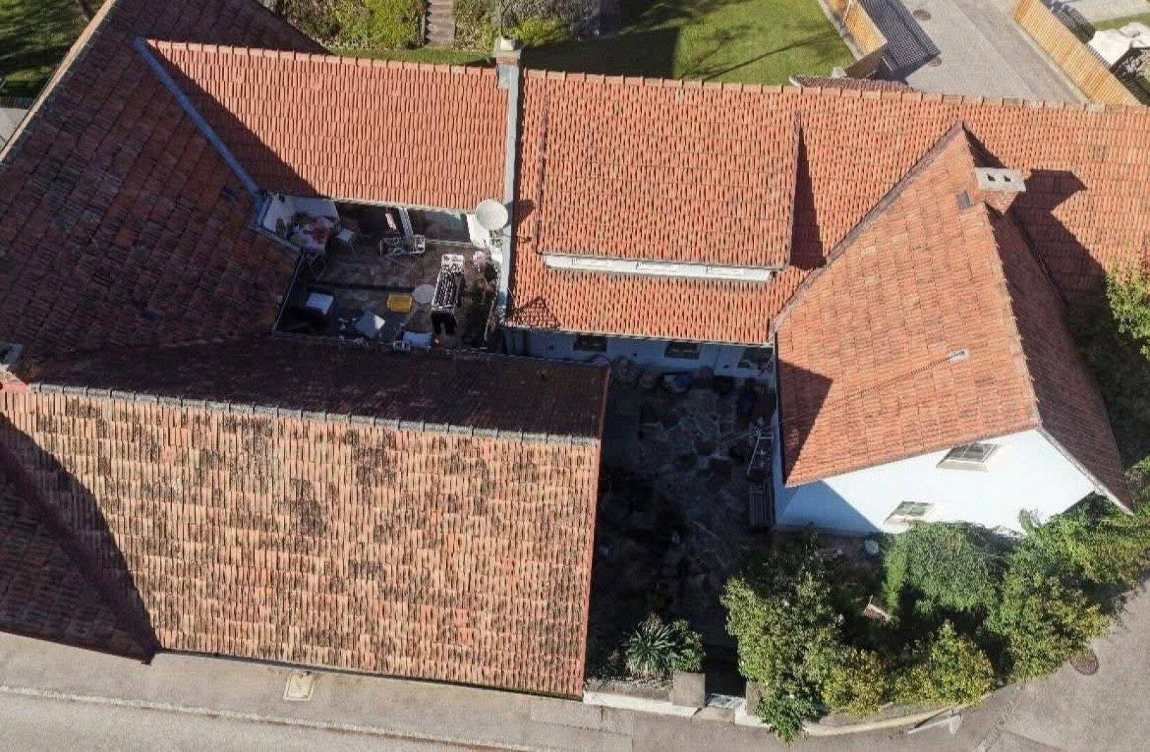 Blick von oben auf einen Innenhof mit Sitzgelegenheiten und den umliegenden Ziegeldächern.