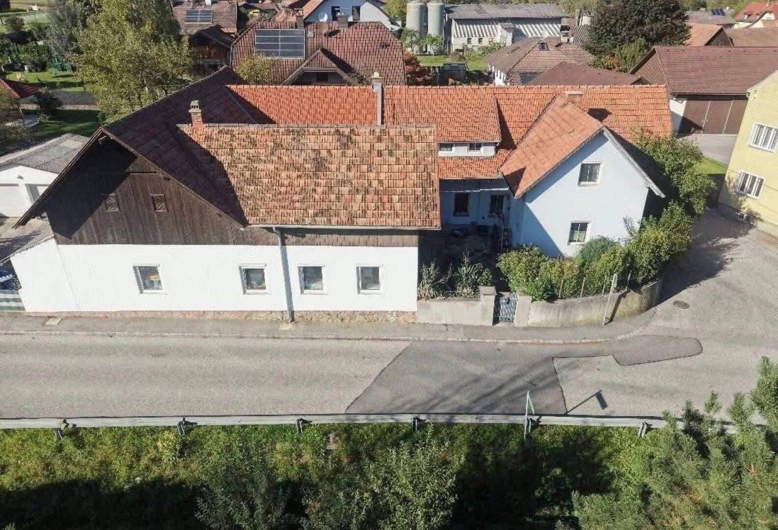 Draufsicht auf das Gebäude mit Ziegeldächern, Solaranlage und angrenzender Straße.
