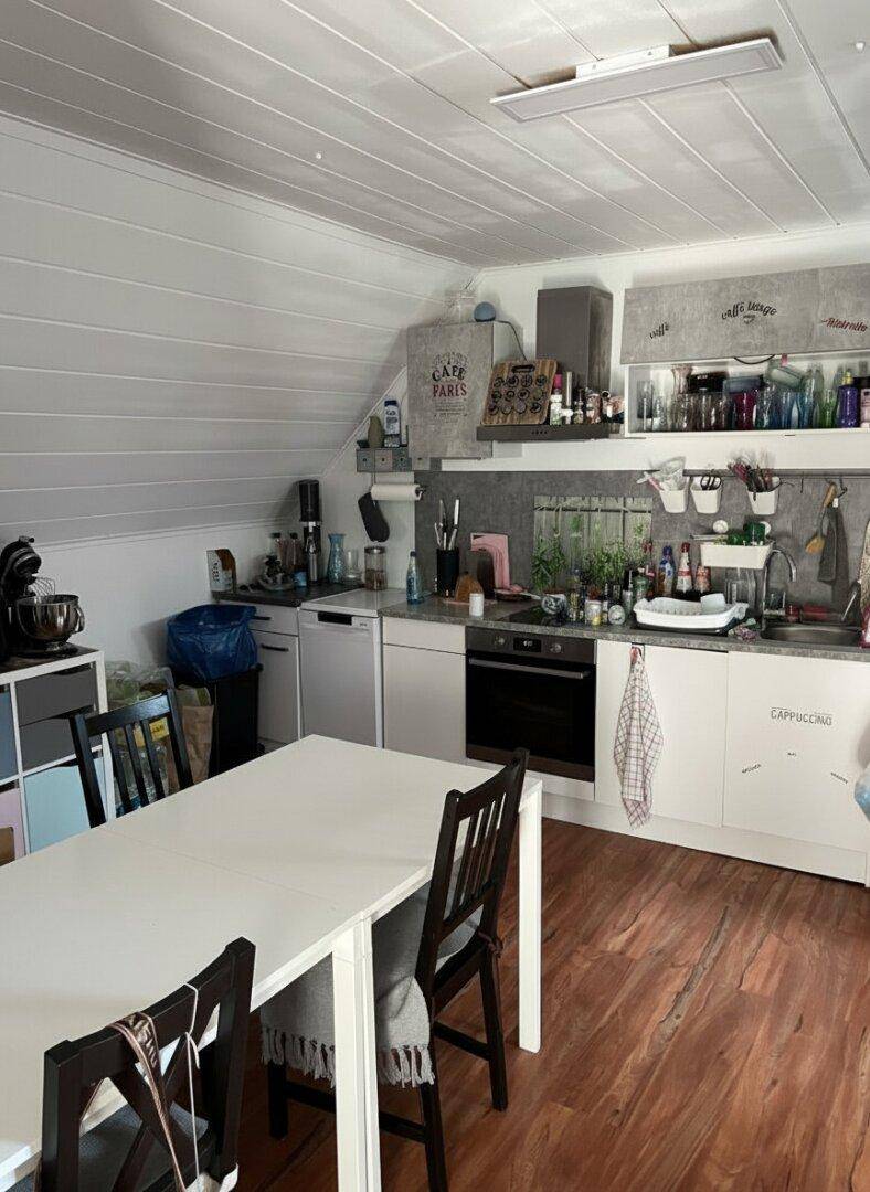 Gemütliche Küche mit Esstisch, Dachschräge und Holzboden.
