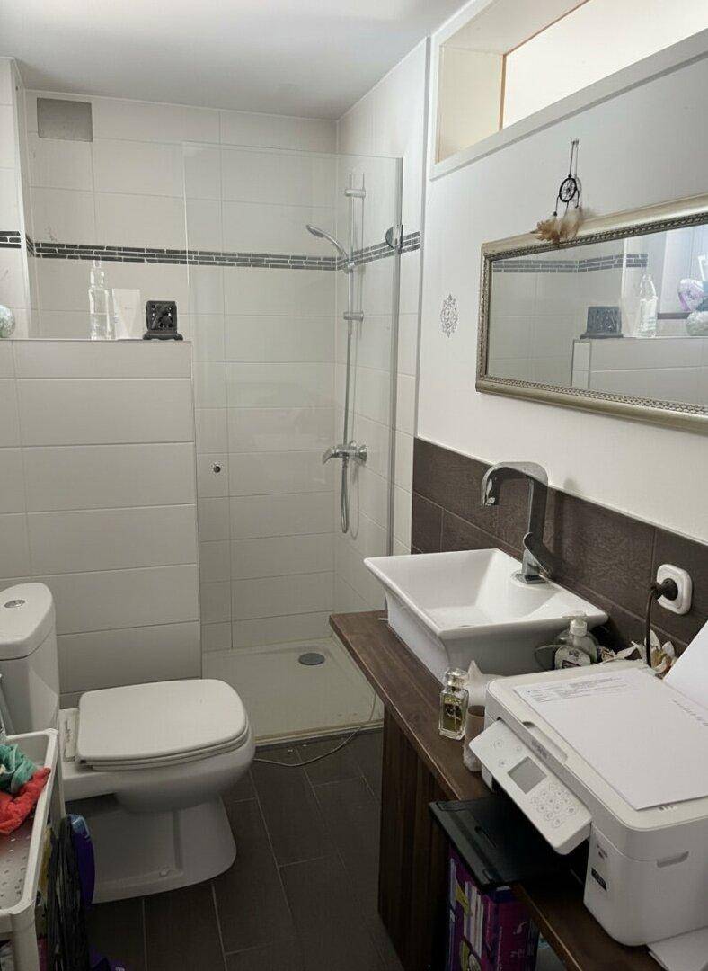 Modernes Badezimmer mit Dusche, weißen Fliesen und einem einzelnen Waschbecken.