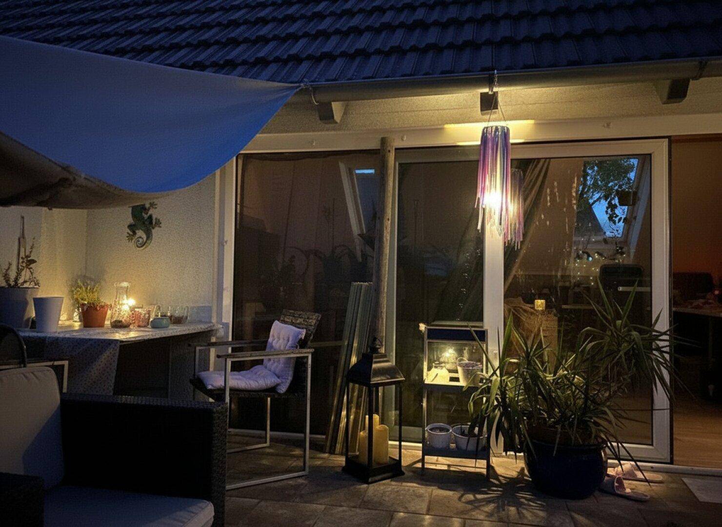 Abendliche Terrasse mit stimmungsvoller Beleuchtung und bequemen Outdoor-Möbeln.
