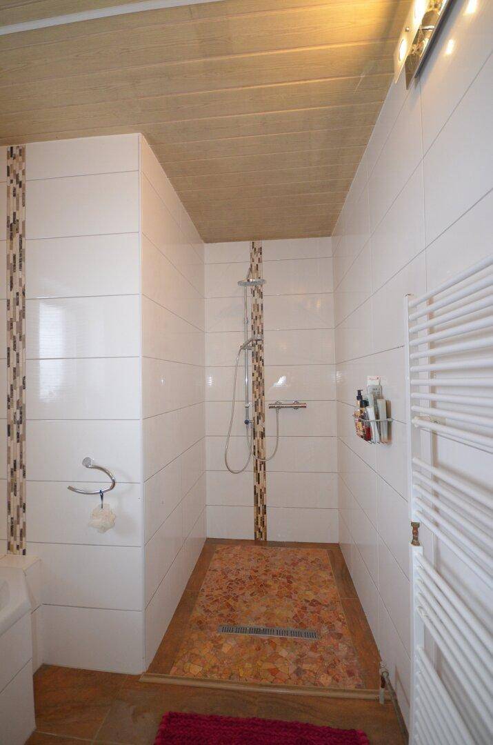 Modern geflieste Dusche mit Mosaikakzenten und beheiztem Handtuchhalter.