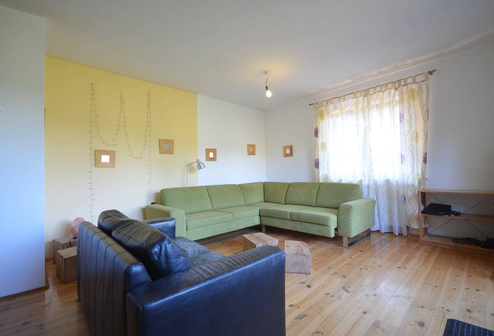 Geräumiges Wohnzimmer mit Holzboden, bequemen Sofas und viel Tageslicht.