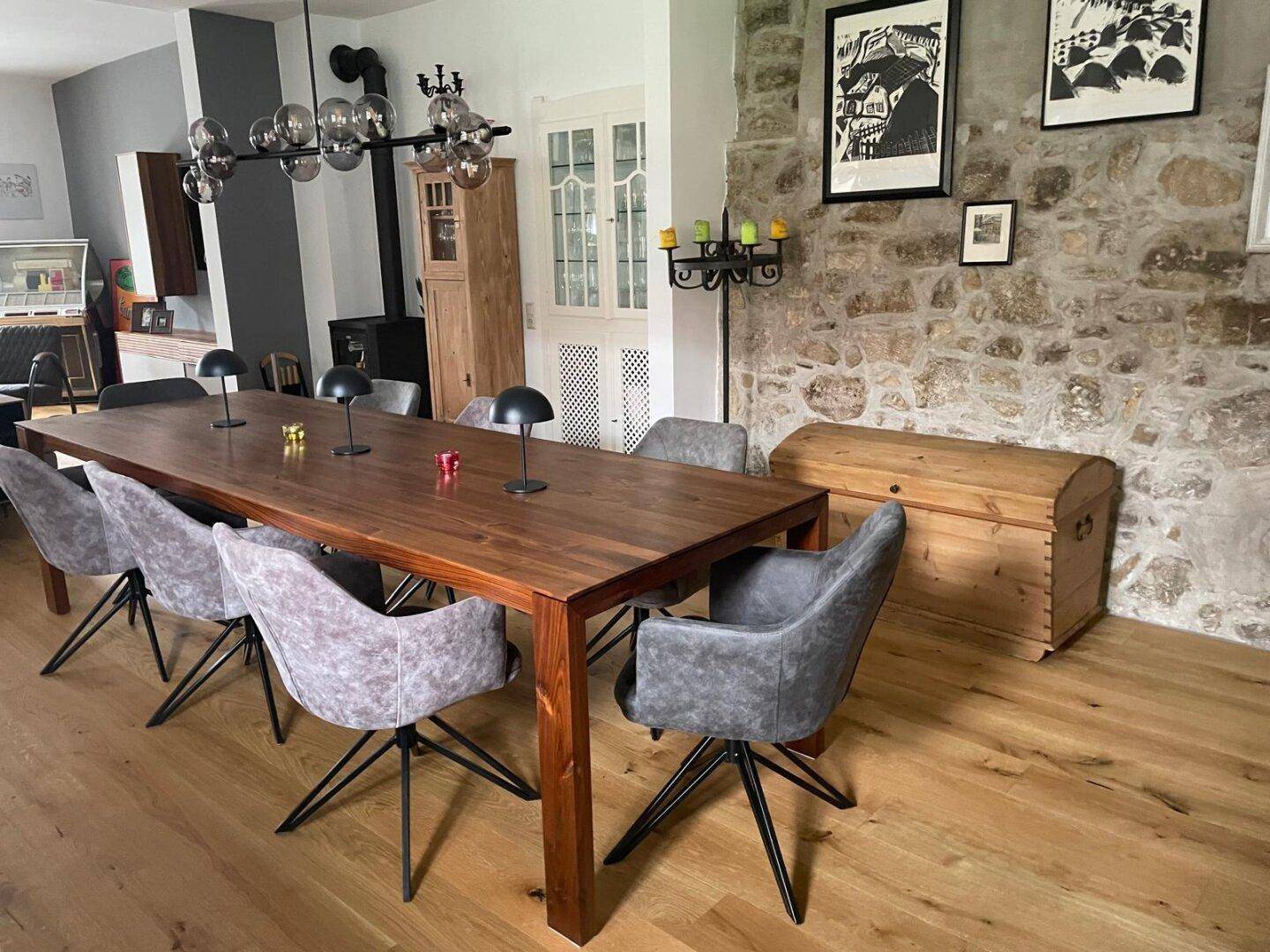 Eleganter Essbereich mit großem Holztisch, bequemen Stühlen und Natursteinwand.