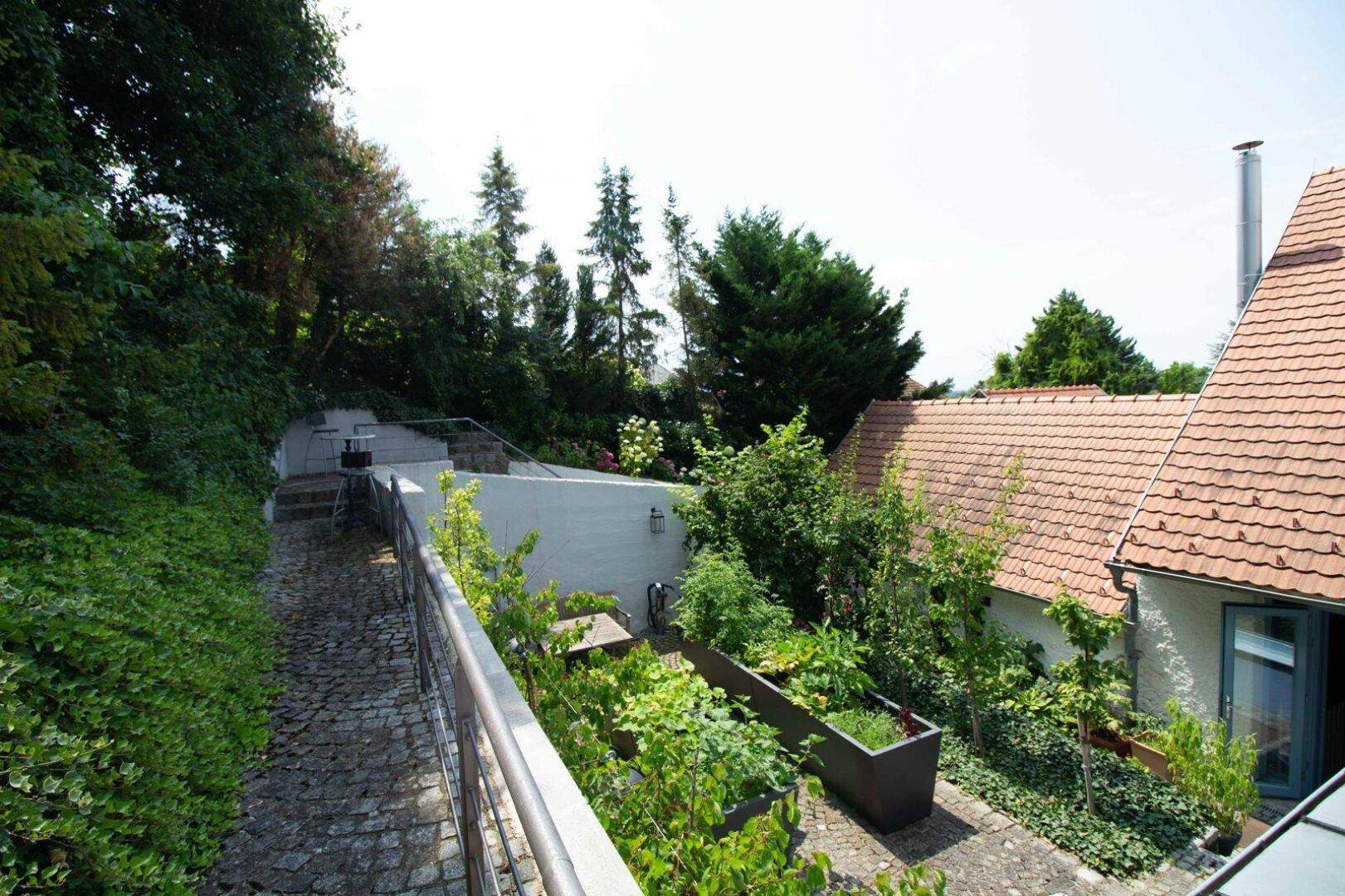 Steinweg führt einen bewachsenen Hang hinauf neben dem Gebäude.