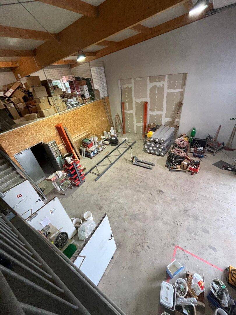 Große Lagerhalle mit Betonboden, Trockenbauwänden und verschiedenen Baumaterialien.