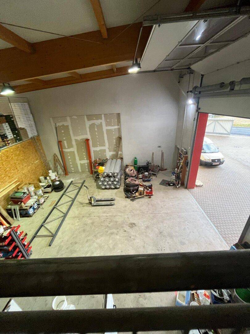 Blick von oben in eine Lagerhalle mit Betonboden, Trockenbauwänden und einem geöffneten Rolltor.