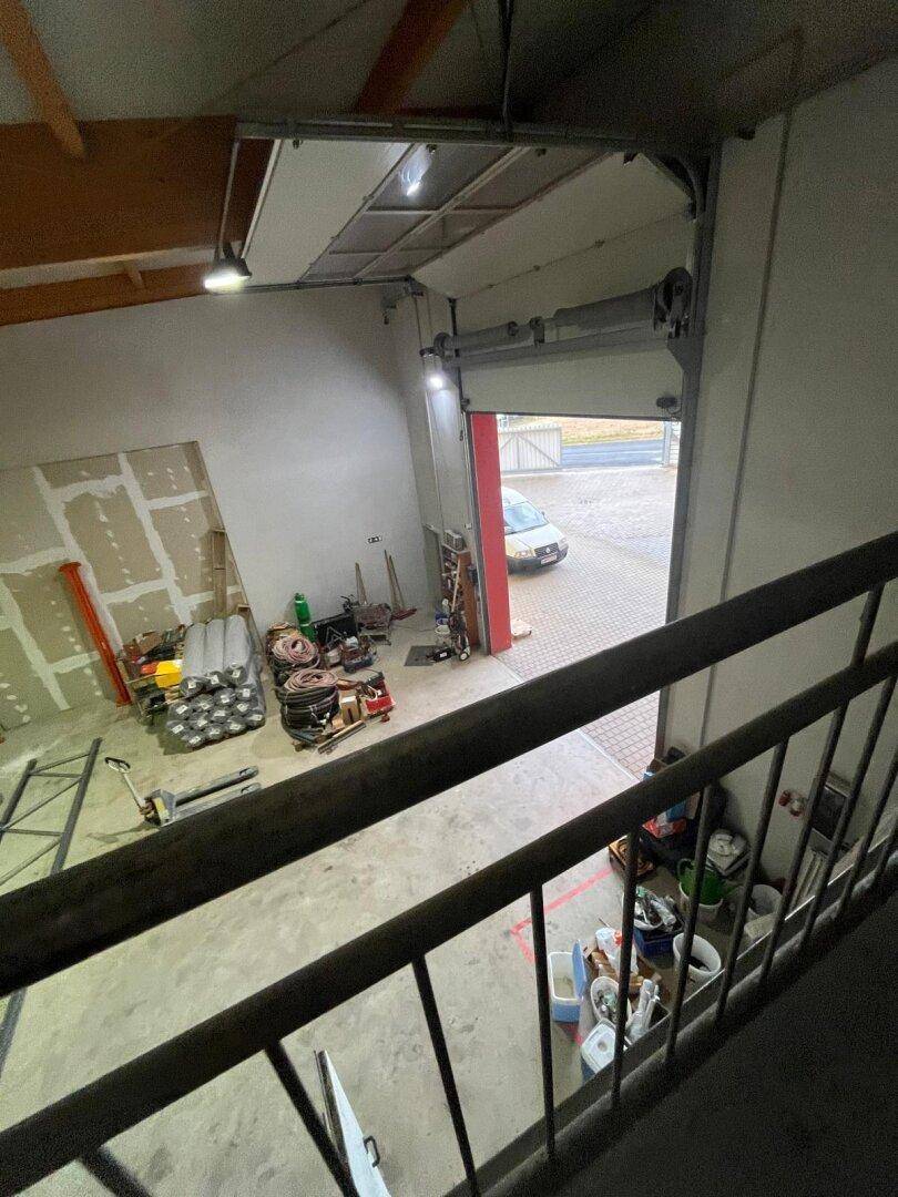 Blick von oben in eine Lagerhalle mit Betonboden, Trockenbauwänden und einem geöffneten Rolltor.