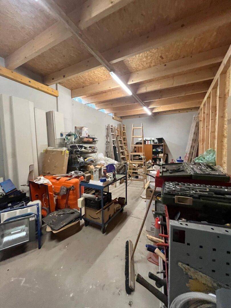 Lagerraum mit Holzbalken, unfertigen Wänden und verschiedenen Werkzeugen und Materialien.