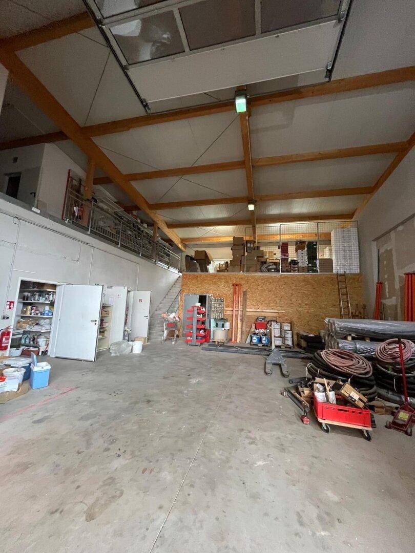 Weitläufige Lagerhalle mit hohen Holzdecken und Betonboden, genutzt für Lagerung und Arbeitsbereiche.