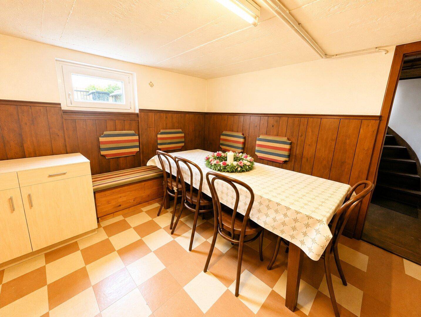 Gemütlicher Essbereich im Keller mit Holzvertäfelung und großem Esstisch.