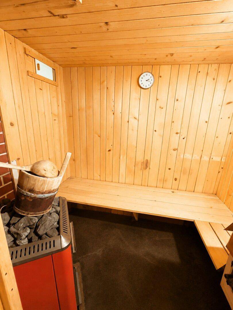 Holzvertäfelte Sauna mit Sitzbänken und Saunaofen für Entspannung.