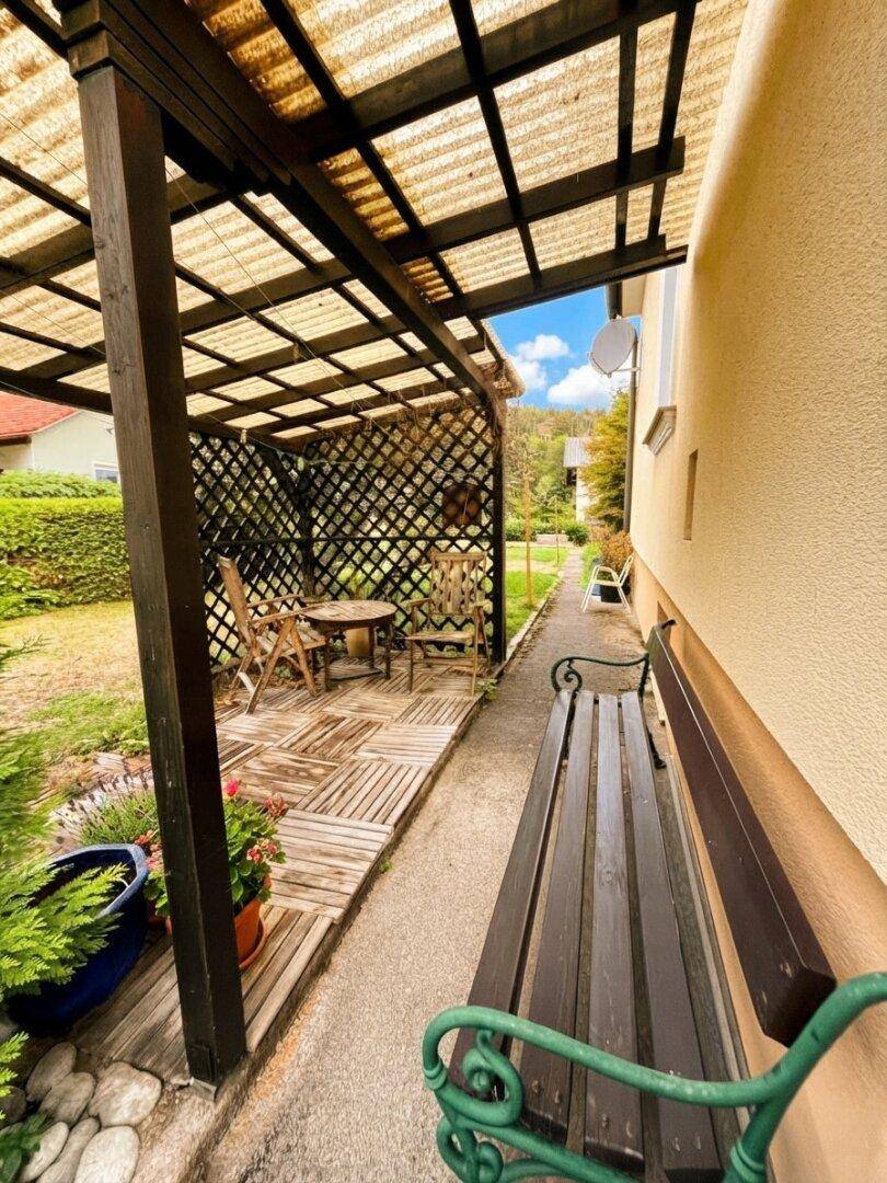 Überdachte Terrasse mit Holzboden und Gartenmöbeln, ideal für entspannte Stunden im Freien.