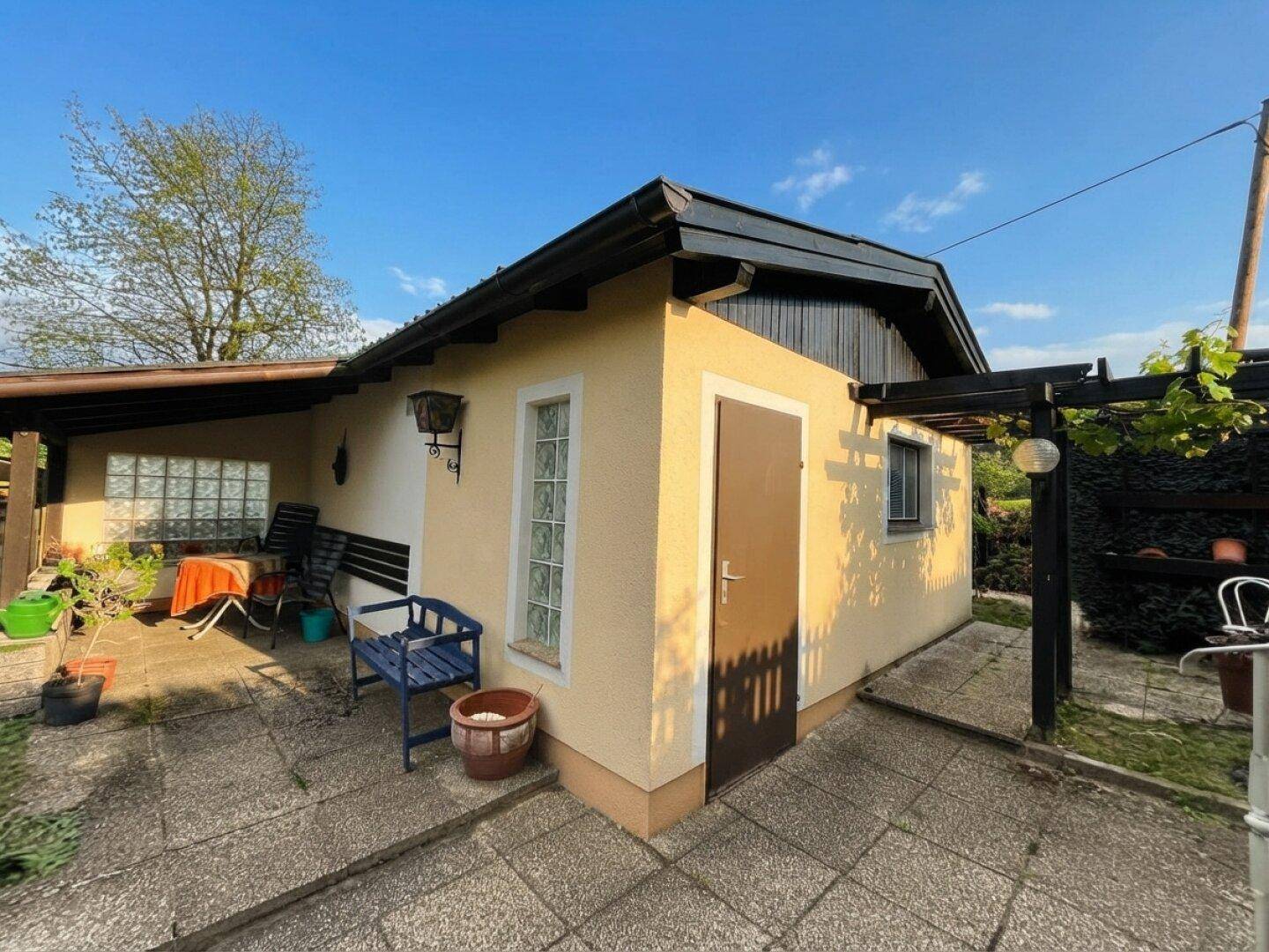 Kleines Nebengebäude mit gepflastertem Bereich und Sitzgelegenheiten im Freien.
