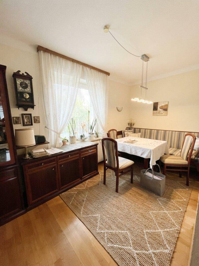 Gemütlicher Essbereich mit traditionellen Holzmöbeln, Teppich und Blick in den Garten.