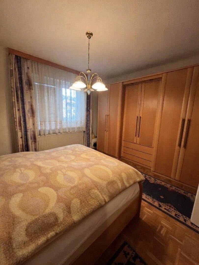 Schlafzimmer mit Doppelbett, Einbauschränken aus Holz und einem Fenster mit Vorhängen.