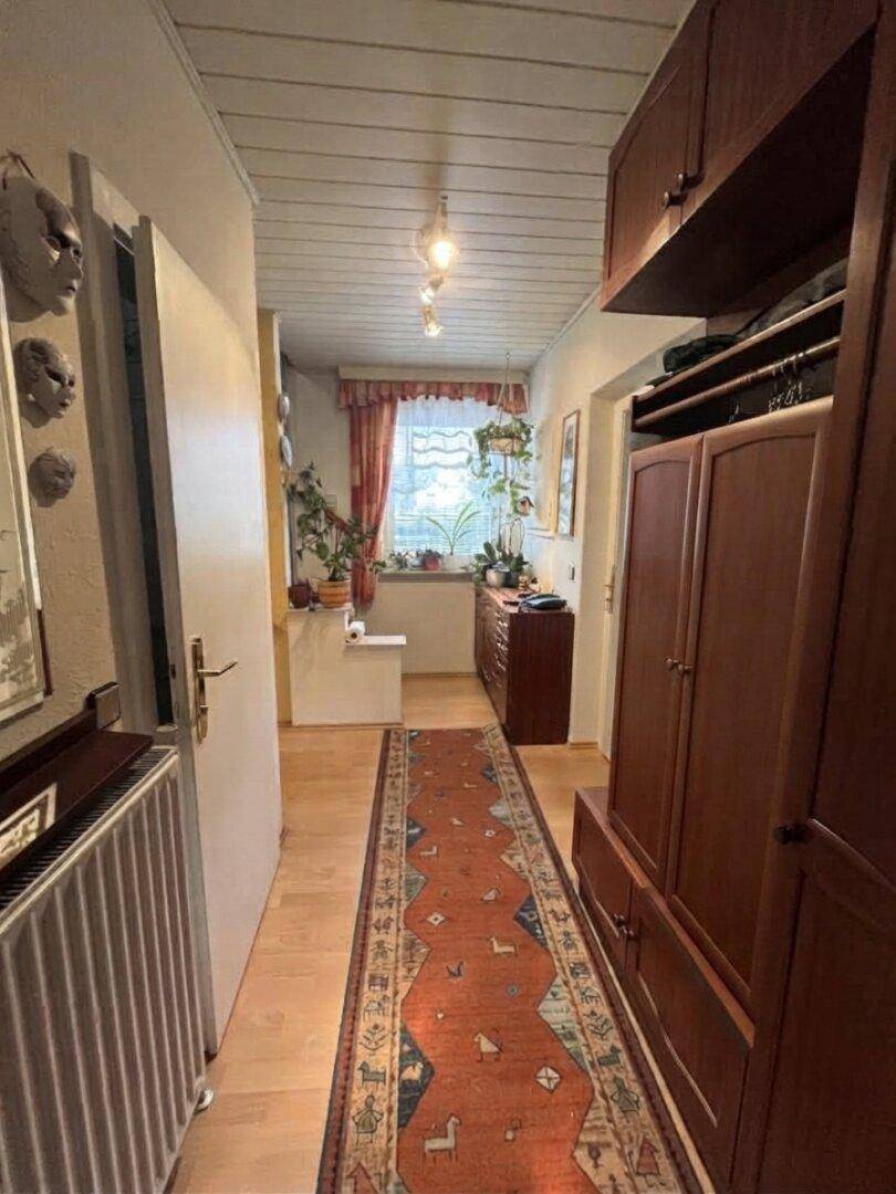 Langer Flur mit Holzdecke, Teppichläufer und Stauraum, der zu weiteren Räumen führt.