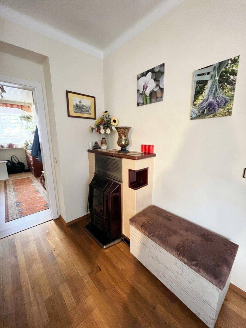 Flur mit Holzboden, einem traditionellen Kachelofen und dekorativen Bildern an der Wand.