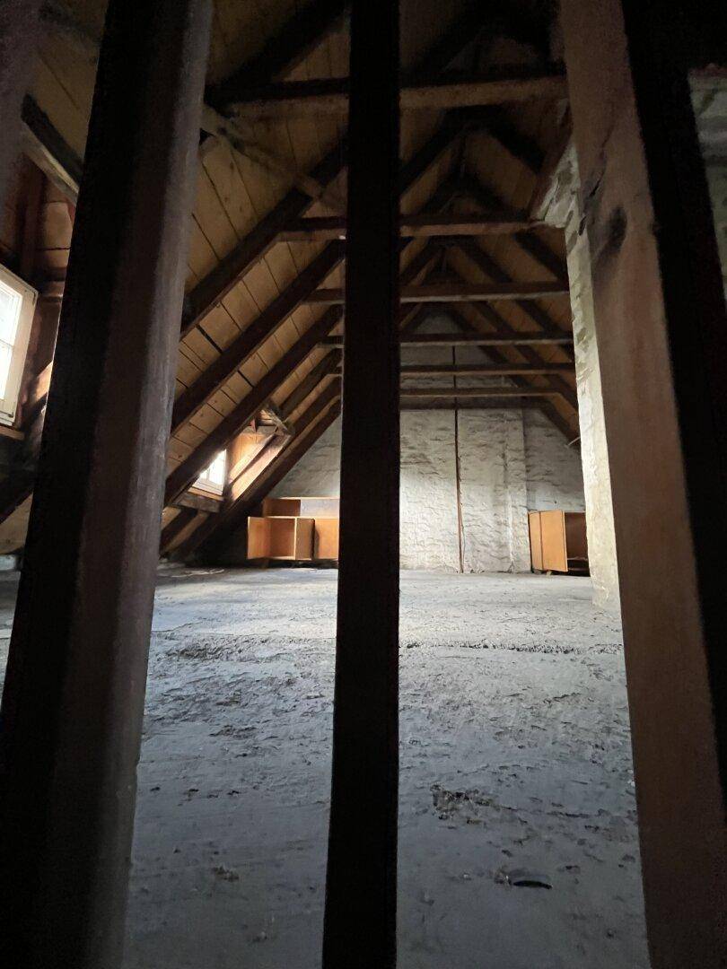 Geräumiger Dachboden mit sichtbaren Holzbalken und Fenstern, bietet Ausbaupotenzial.