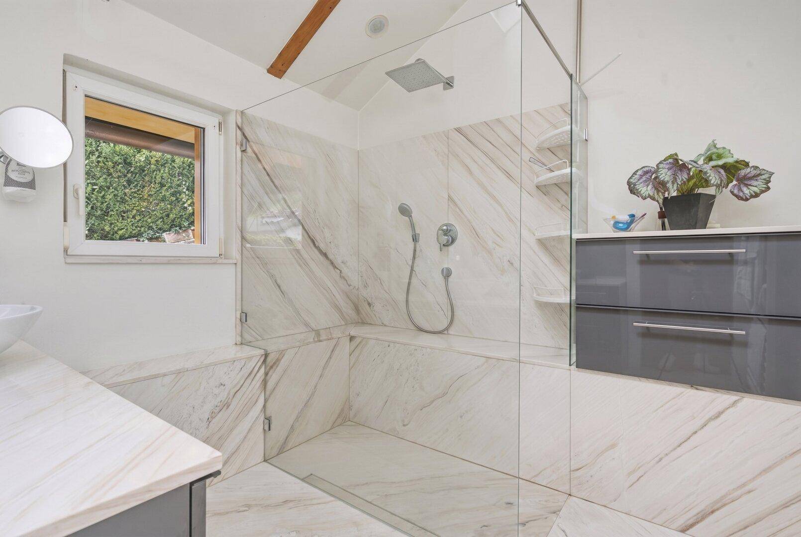 Modernes Badezimmer mit großer begehbarer Dusche, Marmorfliesen und Fenster.