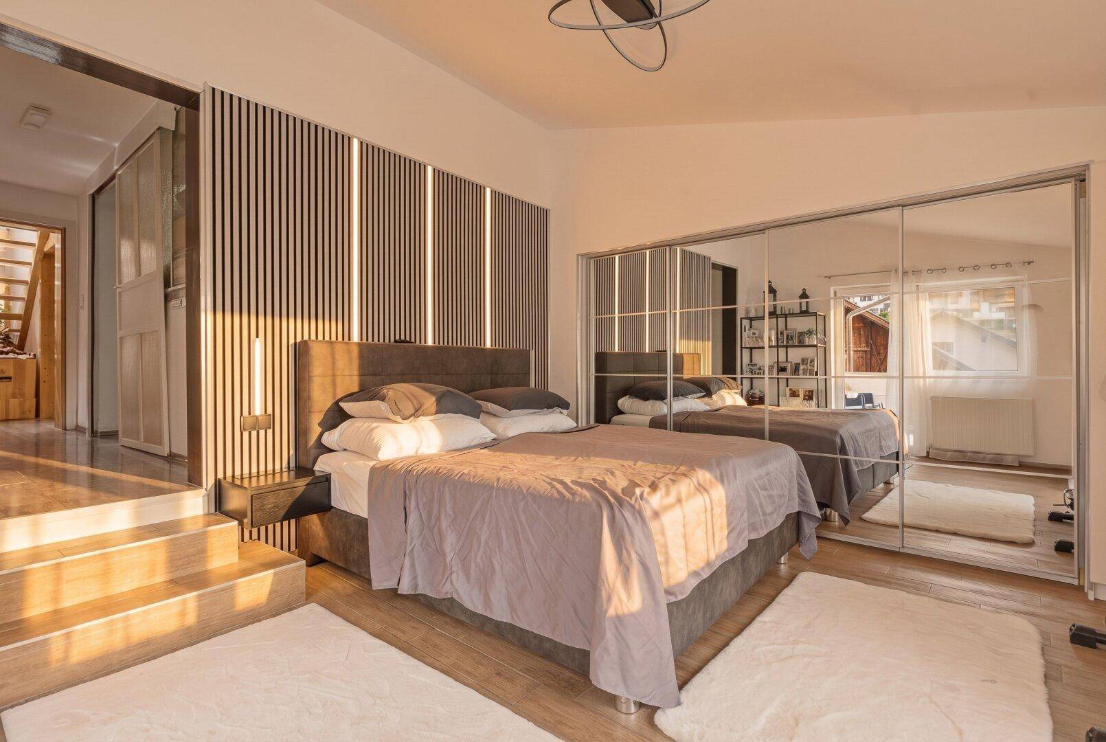 Gemütliches Schlafzimmer mit großem Bett, Spiegelschränken und Holzboden.