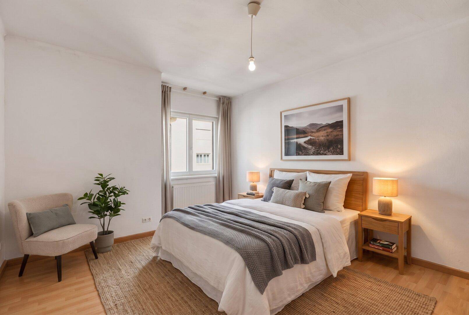 Modern eingerichtetes Schlafzimmer mit Doppelbett, Nachttischen und einem Fenster mit Vorhängen.