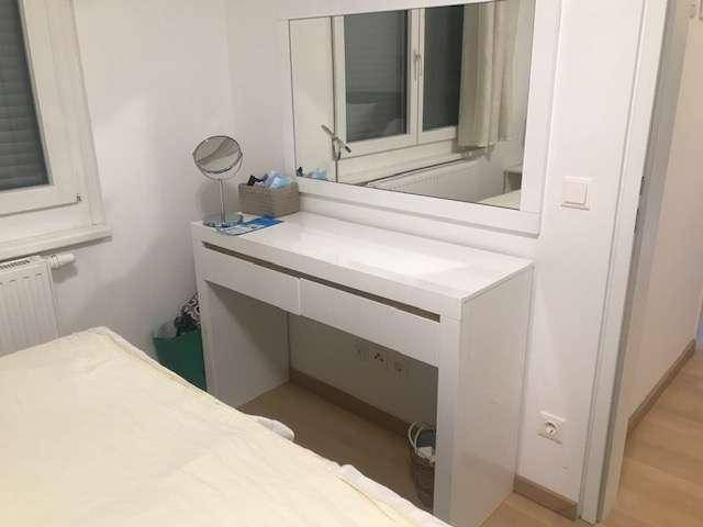 Schlafzimmer mit einem weißen Schminktisch und großem Spiegel, ideal für die Morgenroutine.