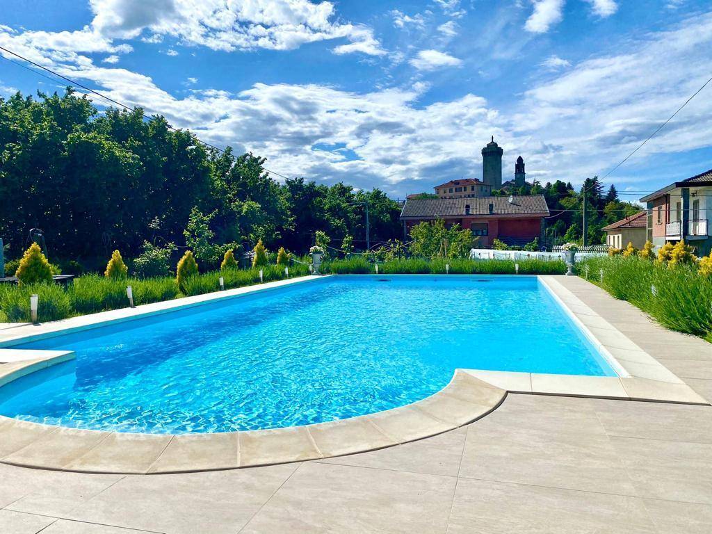 Großer, sauberer Swimmingpool mit gepflegter Umgebung und Blick auf ein historisches Dorf.