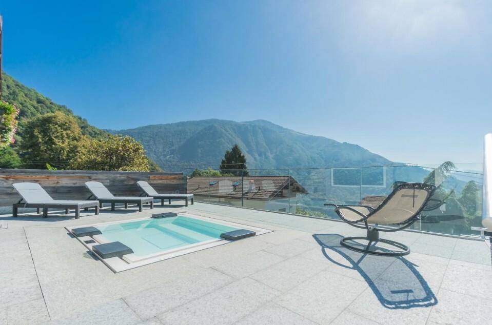 Großzügige Terrasse mit integriertem Whirlpool, Liegestühlen und atemberaubendem Bergblick.