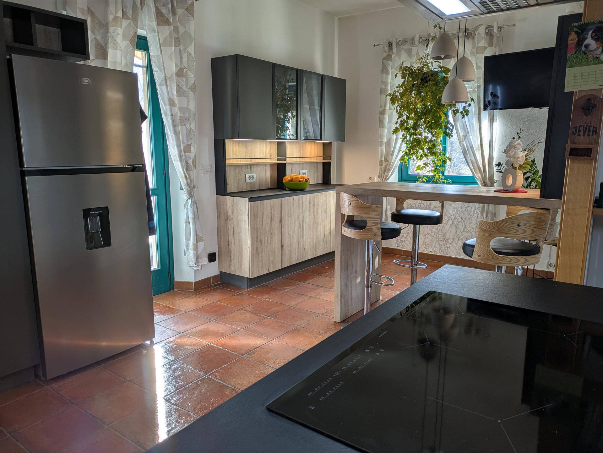 Ansicht der modernen Küche mit großem Kühlschrank, Induktionskochfeld und Frühstücksbar.