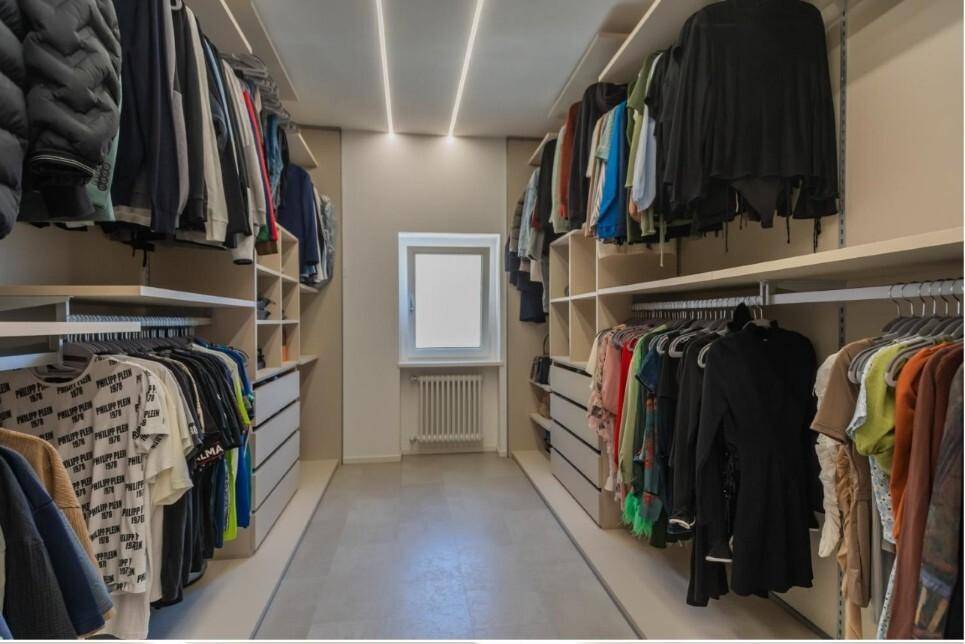 Begehbarer Kleiderschrank mit umfangreichen Regalen und Stauraum sowie einem Fenster.