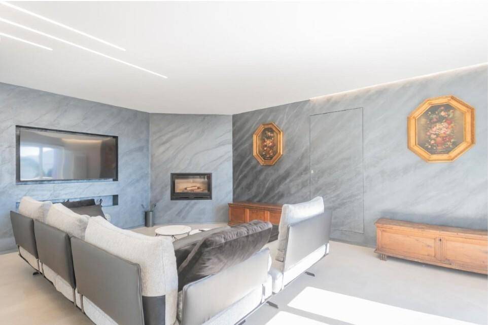 Stilvolles Wohnzimmer mit modernem Kamin, grauen Wänden und indirekter Beleuchtung.