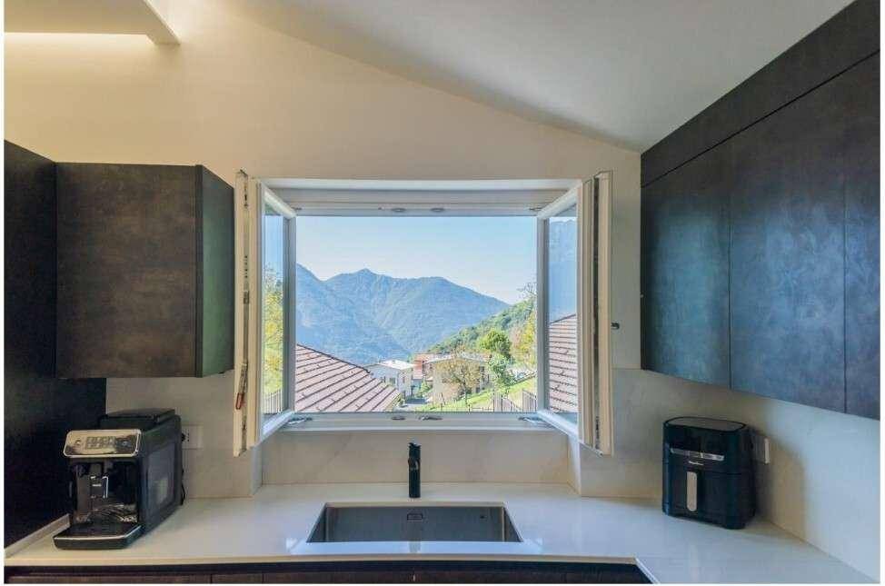 Moderne Küche mit Spülbecken unter einem Fenster, das einen malerischen Blick auf die Berge freigibt.