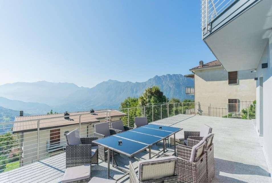 Große Außenterrasse mit Esstisch und Stühlen, ideal für Mahlzeiten im Freien mit Bergblick.