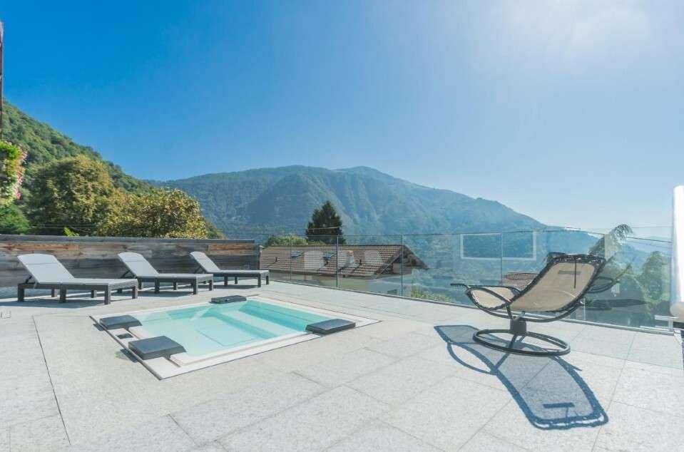 Geräumige Terrasse mit integriertem Whirlpool und Liegestühlen, die einen atemberaubenden Bergblick bietet.