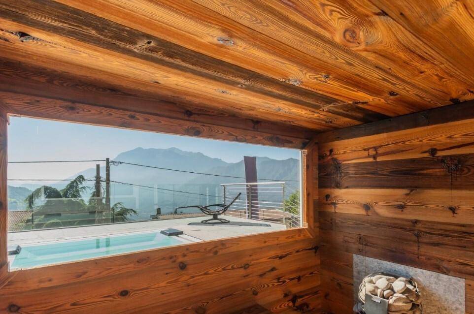 Gemütlicher Wellnessbereich mit Holzverkleidung, kleinem Pool und Panoramablick auf die Berge.