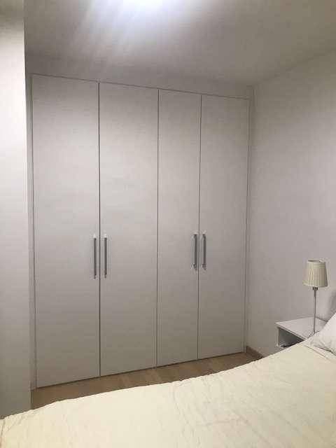 Schlafzimmer mit großen, weißen Einbauschränken, die viel Stauraum bieten.