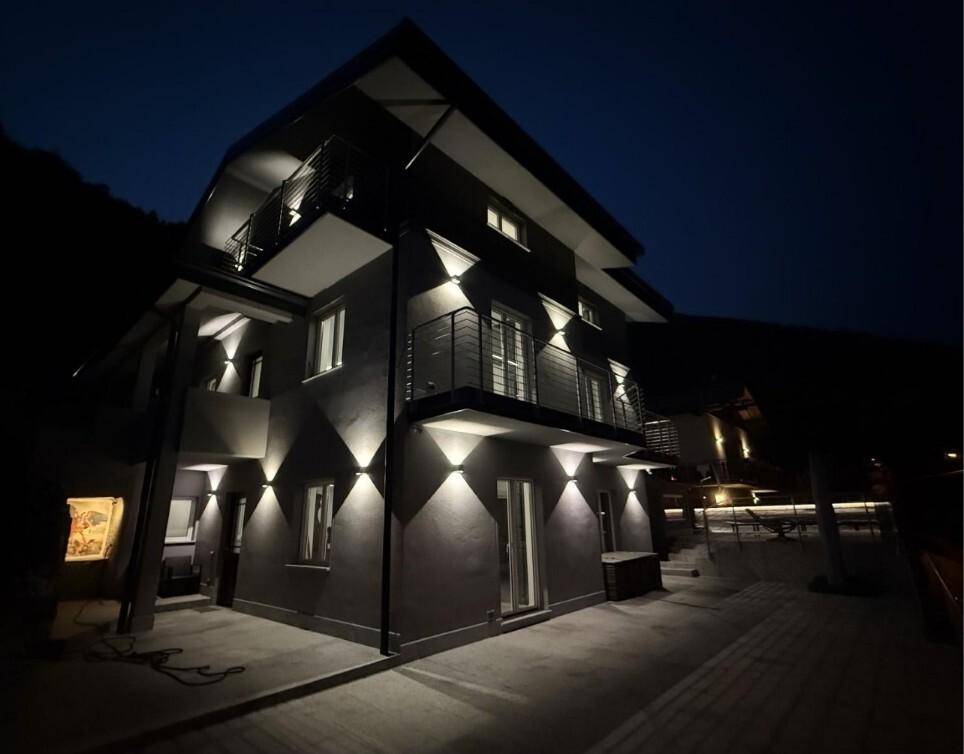 Moderne Gebäudefassade bei Nacht, eindrucksvoll beleuchtet und mit Balkonen ausgestattet.